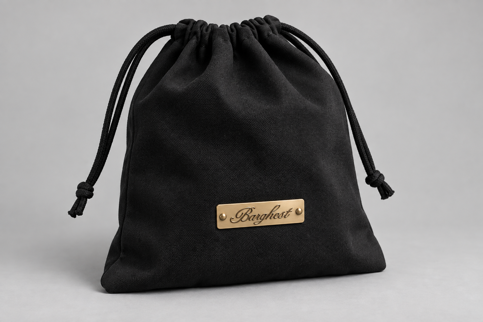 Black canvas drawstring cap bag with a brass Barghest badge riveted to the lower half using two brass rivets